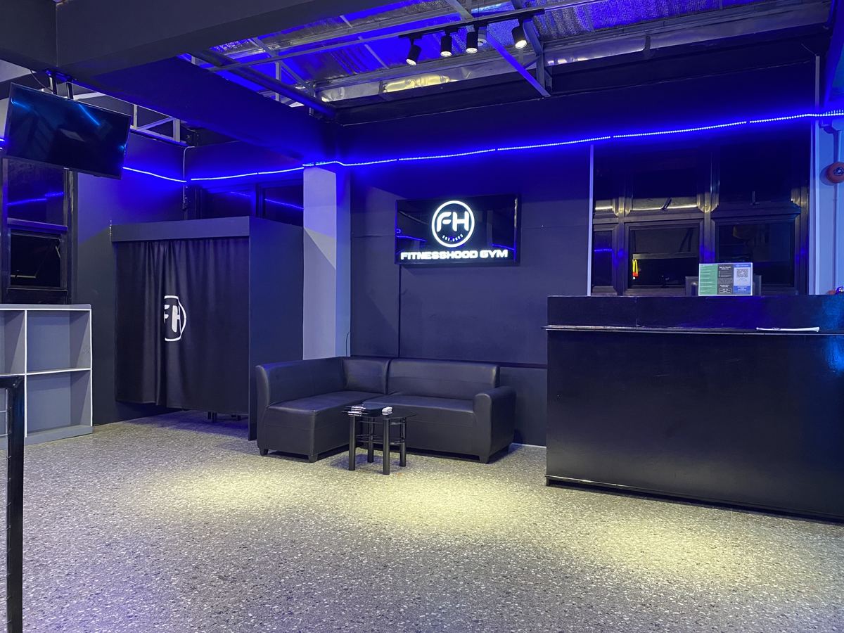 Reception lounge with the lit FitnessHood Gym sign