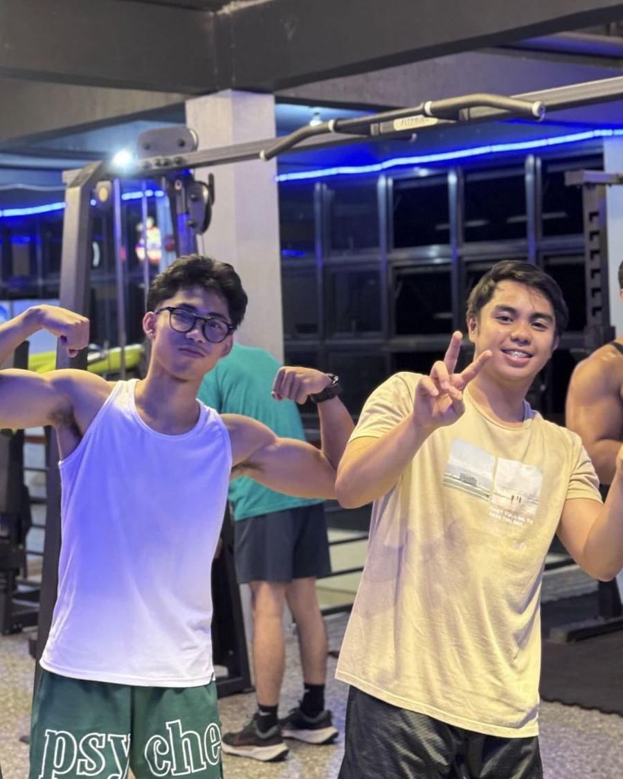 Two FitnessHood members flexing on the gym floor